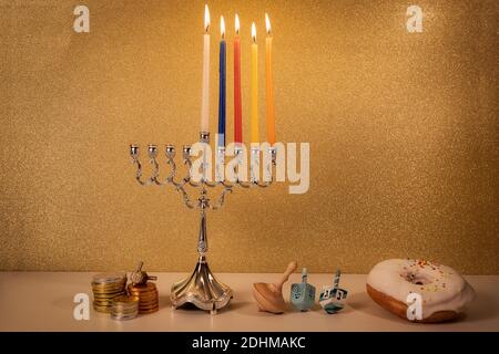 Jour 4 de vacances religieuses juives Hanukkah avec menorah chandelier traditionnel, jouets à tourbillonner (rêdels) et un donut et pièces de chocolat sur whi Banque D'Images