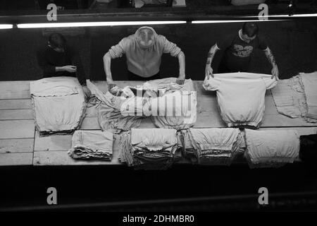 John Smedley de tricots fins / les travailleurs masculins laver et trier les vêtements selon la taille avant de presser , Derbyshire, Royaume-Uni Banque D'Images