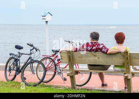 Alabama Fairhope Municipal Park Pier Mobile Bay, homme femme couple vélos motards se reposant banc, Banque D'Images