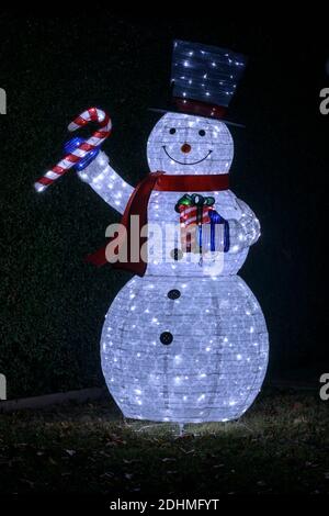 Bonhomme de neige à porter un chapeau et une écharpe et portant une canne à sucre et cadeau Banque D'Images