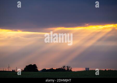 Rayons du soleil piquant des nuages gris sur un champ vert Banque D'Images