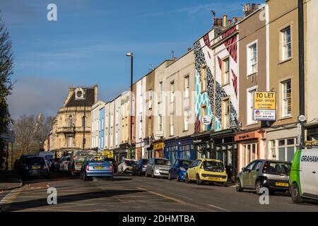 Le soleil brille sur les maisons traditionnelles en terrasse de densité moyenne et les petites boutiques Sur Midland Road dans le quartier Old Market de Bristol.on- Banque D'Images