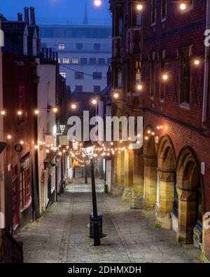 Les lumières illuminent la vieille rue pittoresque des magasins lors des marches de Noël lors d'un matin d'hiver brumeux à Bristol. Banque D'Images