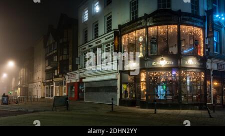 Les boutiques sont décorées pour Noël à High Street Corner lors d'une nuit brumeuse à Bristol. Banque D'Images