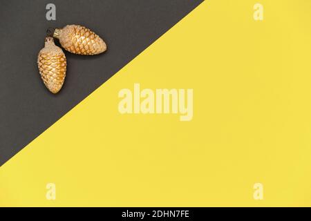 Composition de Noël dans les couleurs de l'année 2021 illuminant et gris. Cônes de pin doré de Noël sur fond gris et jaune. Banque D'Images
