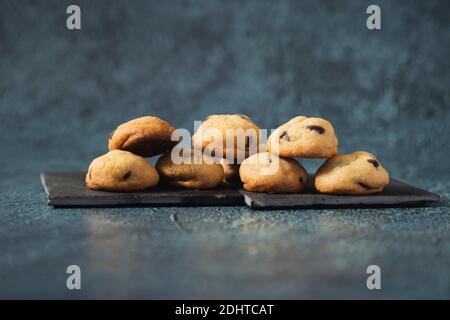 Petits biscuits aux pépites de chocolat servis sur une élégante assiette noire - collations gastronomiques Banque D'Images