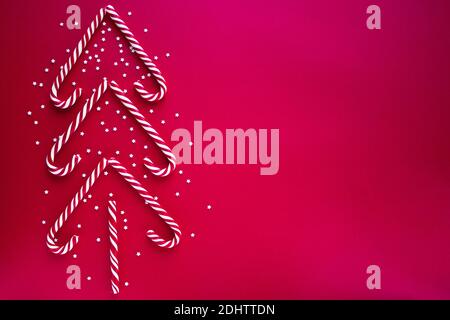 Cannes en sucre formant un arbre de Noël. Bâtonnets rouges doux avec de petites étoiles. Pose à plat, vue de dessus. Affiche, bannière, modèle de carte de vœux. Un retour festif Banque D'Images