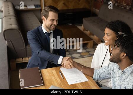 Heureux couple biracial poignée de main homme Realtor à la réunion Banque D'Images