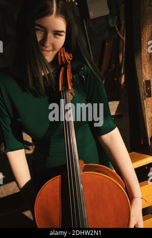 Adolescente avec violoncelle, posant dans un hall. Banque D'Images