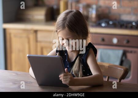 Gros plan sourire petite fille en utilisant une tablette, assis à une table Banque D'Images