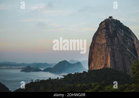 Les téléphériques atteignent le sommet du mont Sugarloaf / Pão de Achçucar au coucher du soleil pour voir les vues sur les baies de Rio de Janeiro et Nitreói, Brésil Banque D'Images