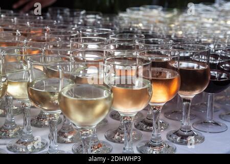 De nombreux verres de vin, de différentes couleurs, en ligne avec un flou sélectif. Les vins rouges, roses et blancs sont visibles, de nombreuses variétés de raisins. Image Banque D'Images