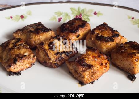 Gros plan de pain de merlu au beurre avec ail et paprika sur une ancienne assiette décorée. Nourriture et poisson. Banque D'Images