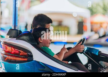 Un petit garçon conduisant une voiture de pare-chocs au carnaval Banque D'Images