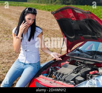 Junge Frau mit einer Motorpanne am Auto Banque D'Images