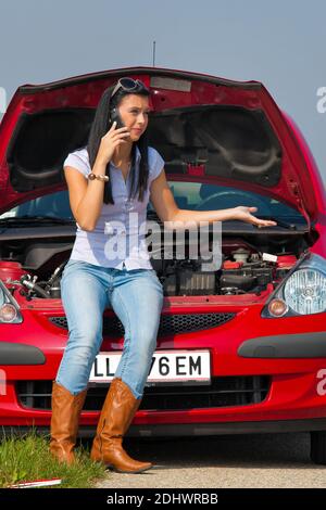 Junge Frau mit einer Motorpanne am Auto Banque D'Images