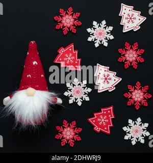 Décoration de Noël, motif blanc et rouge sur fond sombre. Un gnome jouet dans un chapeau conique avec une barbe et des flocons de neige colorés sur un New y noir festif Banque D'Images