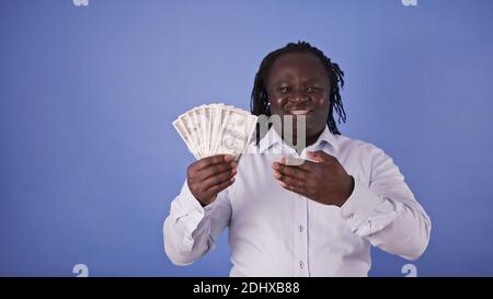 Un jeune homme afro-américain tient de l'argent entre ses mains. Concept de richesse. Photo de haute qualité Banque D'Images