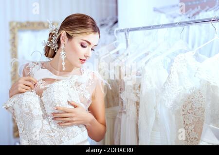 Jeune belle femme choisit une robe dans un salon de mariage. Banque D'Images