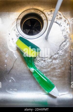 L'eau du robinet s'inverse dans l'évier en acier inoxydable avec l'épurateur de la cuve. Banque D'Images