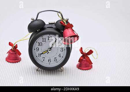 gros plan d'un réveil rétro noir avec trois cloches rouges, isolé sur fond blanc Banque D'Images