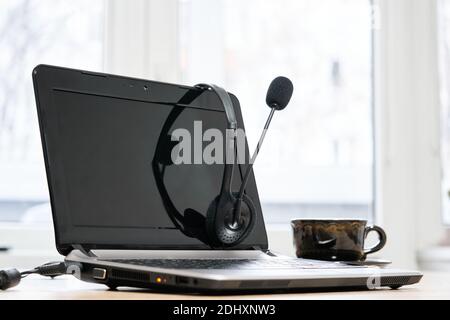 ordinateur portable, casque avec microphone et tasse à café sur la table Banque D'Images