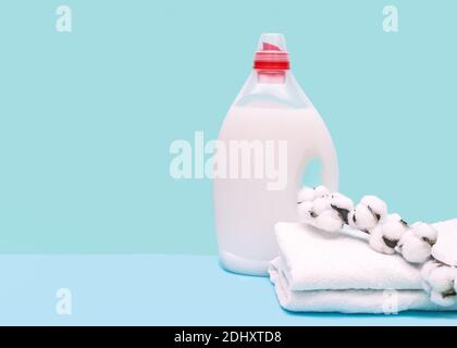 Lessive en bouteille avec liquide et serviettes sur fond bleu avec boule de coton. Concept de lavage Banque D'Images