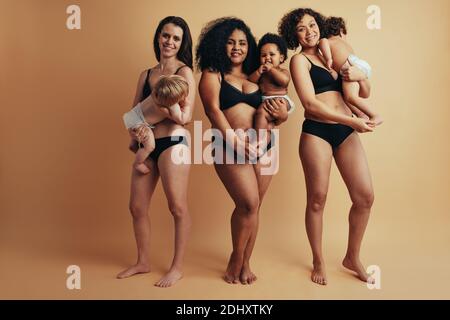 Groupe de trois femmes debout avec leurs bébés. Corps réel des femmes après un an d'accouchement. Banque D'Images