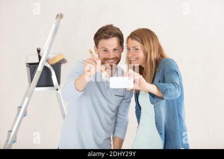 couple à la maison peinture murs prenant selfie avec smartphone Banque D'Images