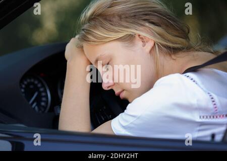 femme dormant sur le volant dans sa voiture Banque D'Images