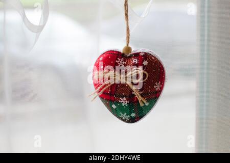 fenêtre de décoration. Ce jouet de sapin de Noël doux fait à la main en tissu rouge et vert avec un noeud de ficelle est accroché à la fenêtre. Nouvelle année an Banque D'Images