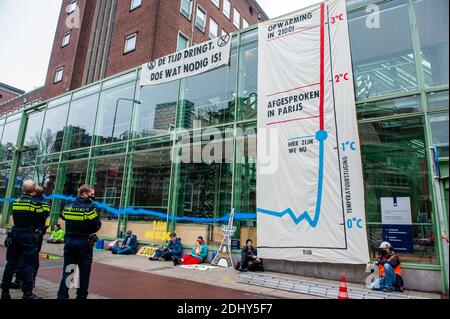 Les policiers sont vus en gardant un œil sur les activistes assis sur le sol pendant la manifestation.les militants du climat de la rébellion d'extinction ont fait un grand pas dans le quartier général du ministère des Affaires économiques et de la politique climatique, en déportant une énorme bannière avertissant d'une urgence climatique et en pulvérisant des peintures sur les fenêtres, Le jour du cinquième anniversaire de l'Accord de Paris sur le climat. Au-delà de Paris, la rébellion de l'extinction exige des émissions nettes de CO2 nulles d'ici 2025. Après quelques heures, la police a déménagé pour enlever et retenir les activistes climatiques qui ont grimpé le bâtiment et ceux qui sont assis sur le sol. Banque D'Images