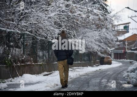 Un homme marche dans une rue enneigée après une première chute de neige à Srinagar.la première chute de neige de la saison a frappé les plaines de la vallée du Cachemire tandis que les hauts sommets du Jammu-et-Cachemire ont subi de fortes chutes de neige. Toutes les autoroutes principales, y compris la Srinagar-Jammu, la Srinagar-Leh et la route Mughal, sont fermées à la circulation à la suite de fortes chutes de neige, ont déclaré les responsables. Banque D'Images