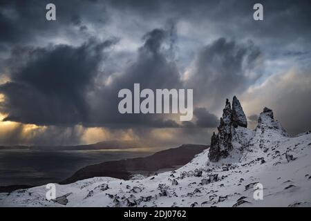 Old Man Storr, Isle Skye, Écosse. Hiver, montagne très enneigée dans un lever de soleil très puissant avec quelques nuages de tempête au milieu du lever du soleil. Banque D'Images