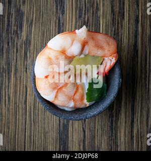 bol de hors-d'œuvre décoratif avec crevettes cuites sur une table en bois, vue sur le dessus Banque D'Images