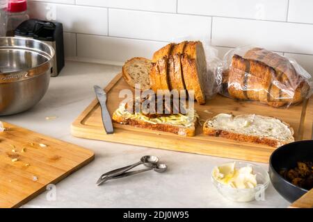 Préparation de croque-monsieur au fromage grillé : assemblage d'un sandwich au fromage grillé recouvert de champignons sautés Banque D'Images