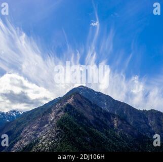 Les nuages de Cirrus s'étendent dans le ciel bleu au-dessus de la montagne près de Lillooet, Colombie-Britannique, Canada. Banque D'Images