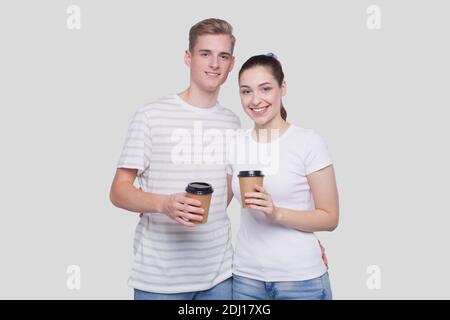 Couple tenant des tasses isolées. Couple debout et tenant le café à aller tasse. Homme et femme embrassant, amoureux, amis, couple concept. Banque D'Images