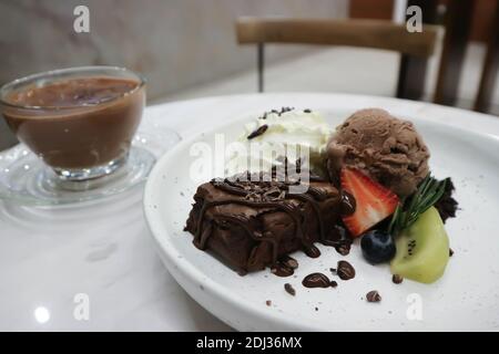 brownie , glace au chocolat avec crème à fouetter et fruits et chocolat chaud Banque D'Images
