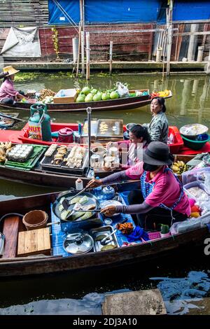 Les femmes à bord de san Pans cuisinent et servent une variété d'en-cas et de plats de rue dans le marché flottant de Damnoen près de Bangkok. Banque D'Images