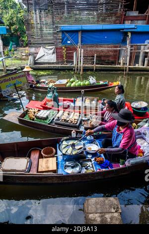 Les femmes à bord de san Pans cuisinent et servent une variété d'en-cas et de plats de rue dans le marché flottant de Damnoen près de Bangkok. Banque D'Images