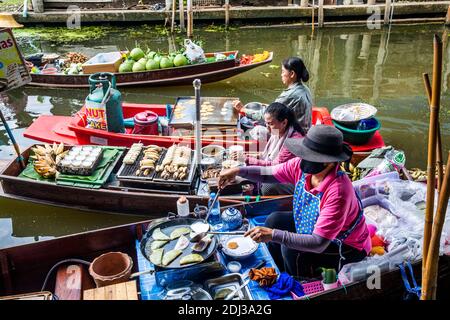 Les femmes à bord de san Pans cuisinent et servent une variété d'en-cas et de plats de rue dans le marché flottant de Damnoen près de Bangkok. Banque D'Images