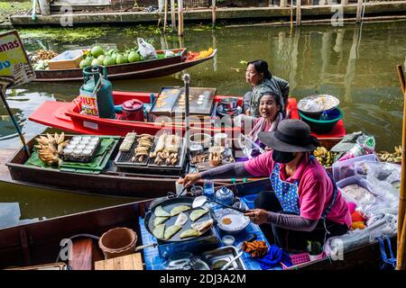 Les femmes à bord de san Pans cuisinent et servent une variété d'en-cas et de plats de rue dans le marché flottant de Damnoen près de Bangkok. Banque D'Images