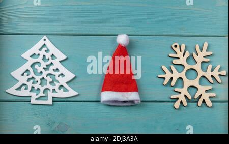 Sur la surface en bois turquoise se trouve un flocon de neige d'arbre et un chapeau de Noël. Banque D'Images