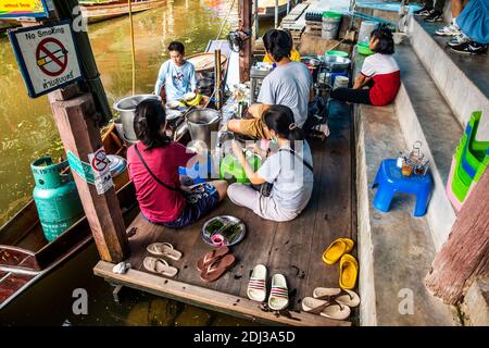 Les femmes à bord de san Pans cuisinent et servent une variété d'en-cas et de plats de rue dans le marché flottant de Damnoen près de Bangkok. Banque D'Images