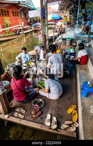 Les femmes à bord de san Pans cuisinent et servent une variété d'en-cas et de plats de rue dans le marché flottant de Damnoen près de Bangkok. Banque D'Images