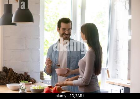 Un homme et une femme heureux qui apprécient les loisirs et qui cuisent la salade ensemble Banque D'Images