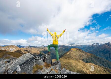 Mountaineer, randonneur qui étire ses bras dans les airs, sommet du Mont Luxmore, vue sur les montagnes Murchison, Kepler Track, Great Walk, Kepler Banque D'Images
