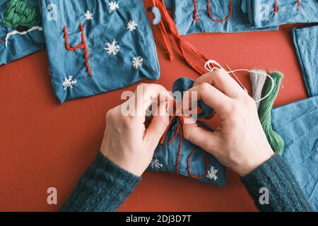 Sacs en tissu pour cadeaux de Noël et numéros faits main avec décorations sur la table. Calendrier de l'Avent fait main pour Noël Banque D'Images