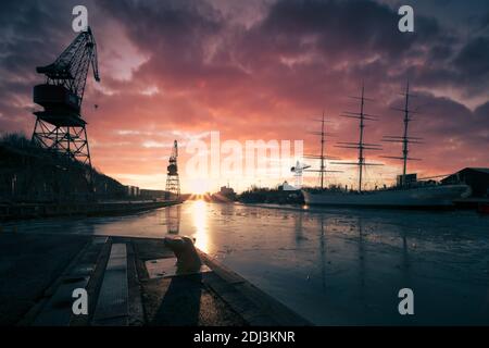 Anciennes grues de construction navale et navire à voile Swan de Finlande avec un coucher de soleil spectaculaire à Turku, Finlande Banque D'Images